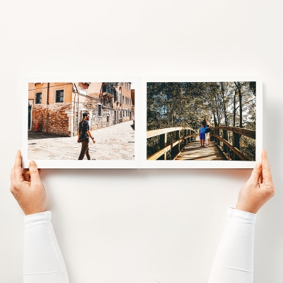 Mains tenant un livre photo ouvert à plat sur une double page sans coupure au centre