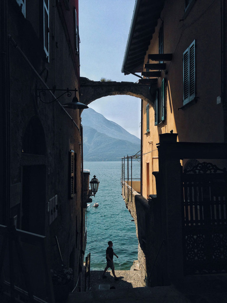 Image shows a brick arch joining a narrow street leading to the ocean. the brick arch shows how effective iphone photography tip: Add A Photo Frame is