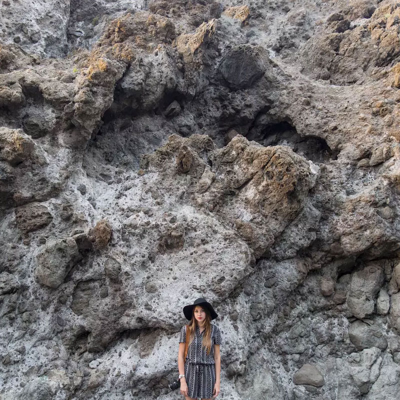 Image taken on an iphone shows a woman in front of a rock face. This image is before edits have taken place.