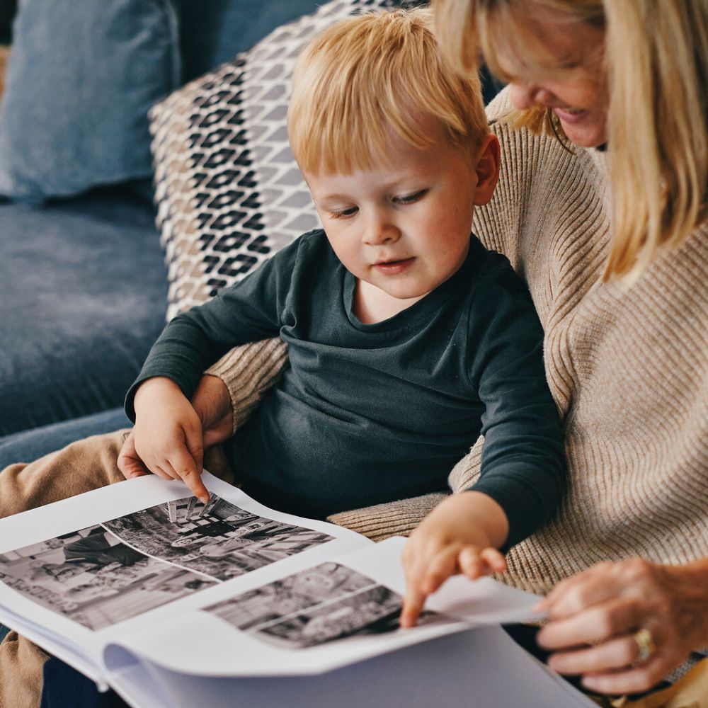 Child pointing at photos in a custom photo book gift for Mother's Day.