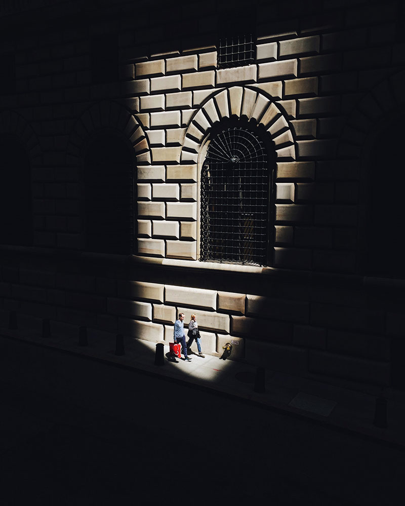Image is taken on a mobile in harsh light. Shadows frame the window of a building.