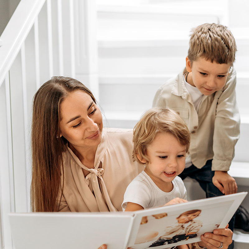 Mother and children looking through a personalised photo book together at home